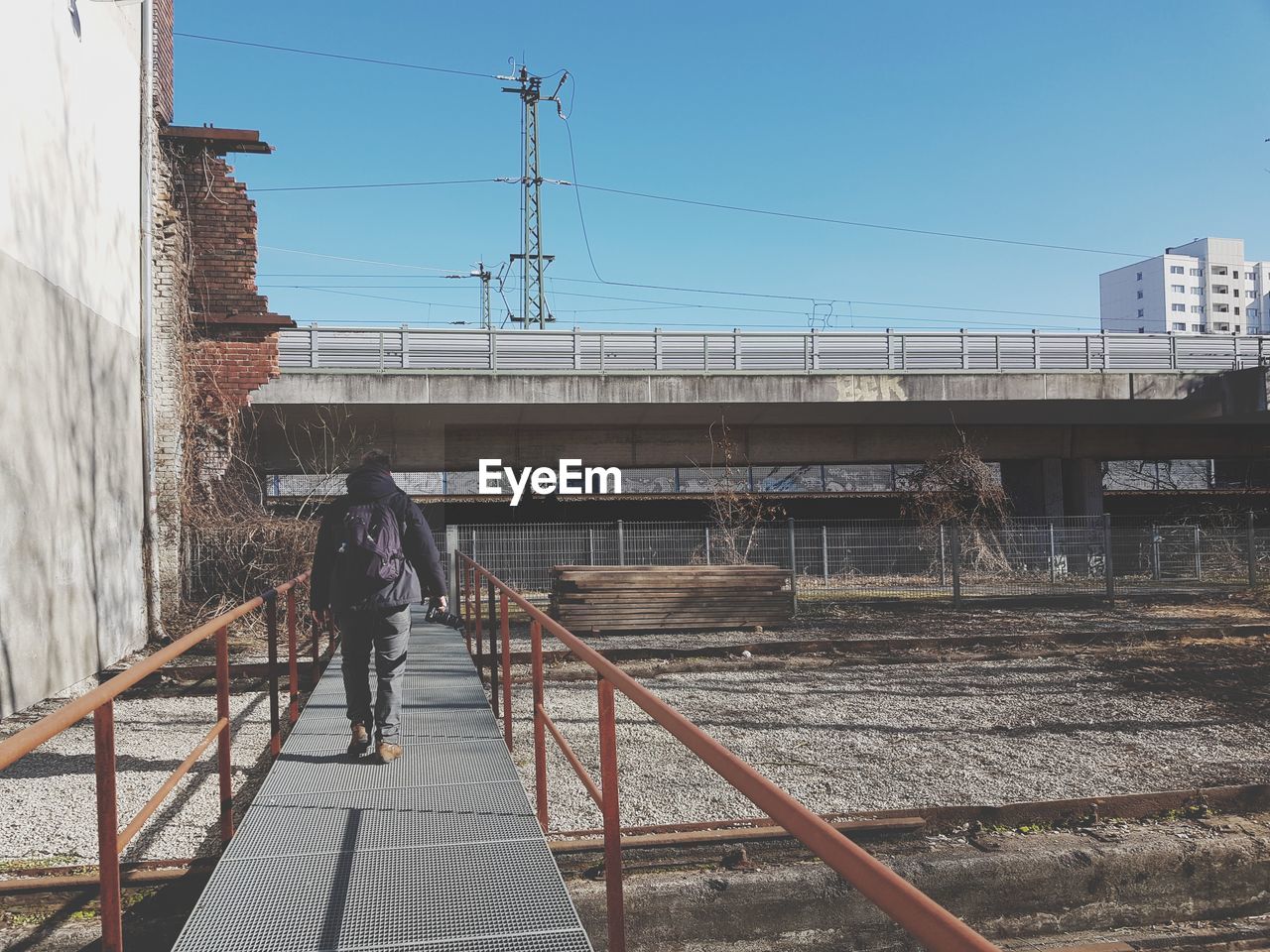 Rear view of man walking on bridge against sky