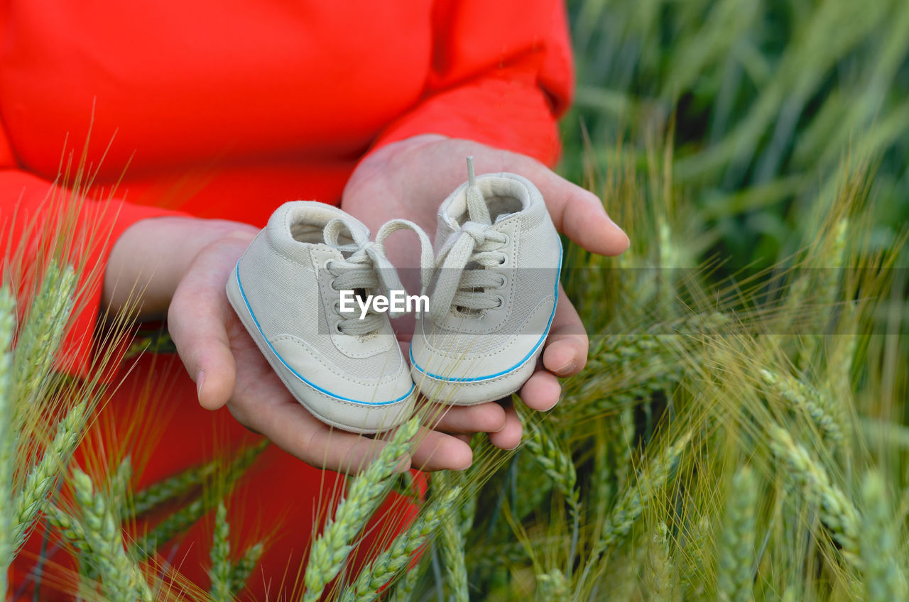 Midsection of woman holding baby booties at farm