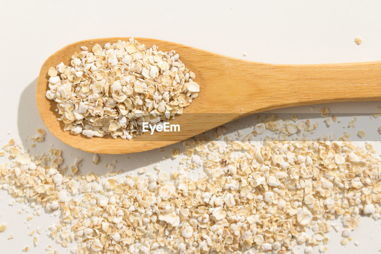 Directly above shot of oat flakes in wooden spoon on white background
