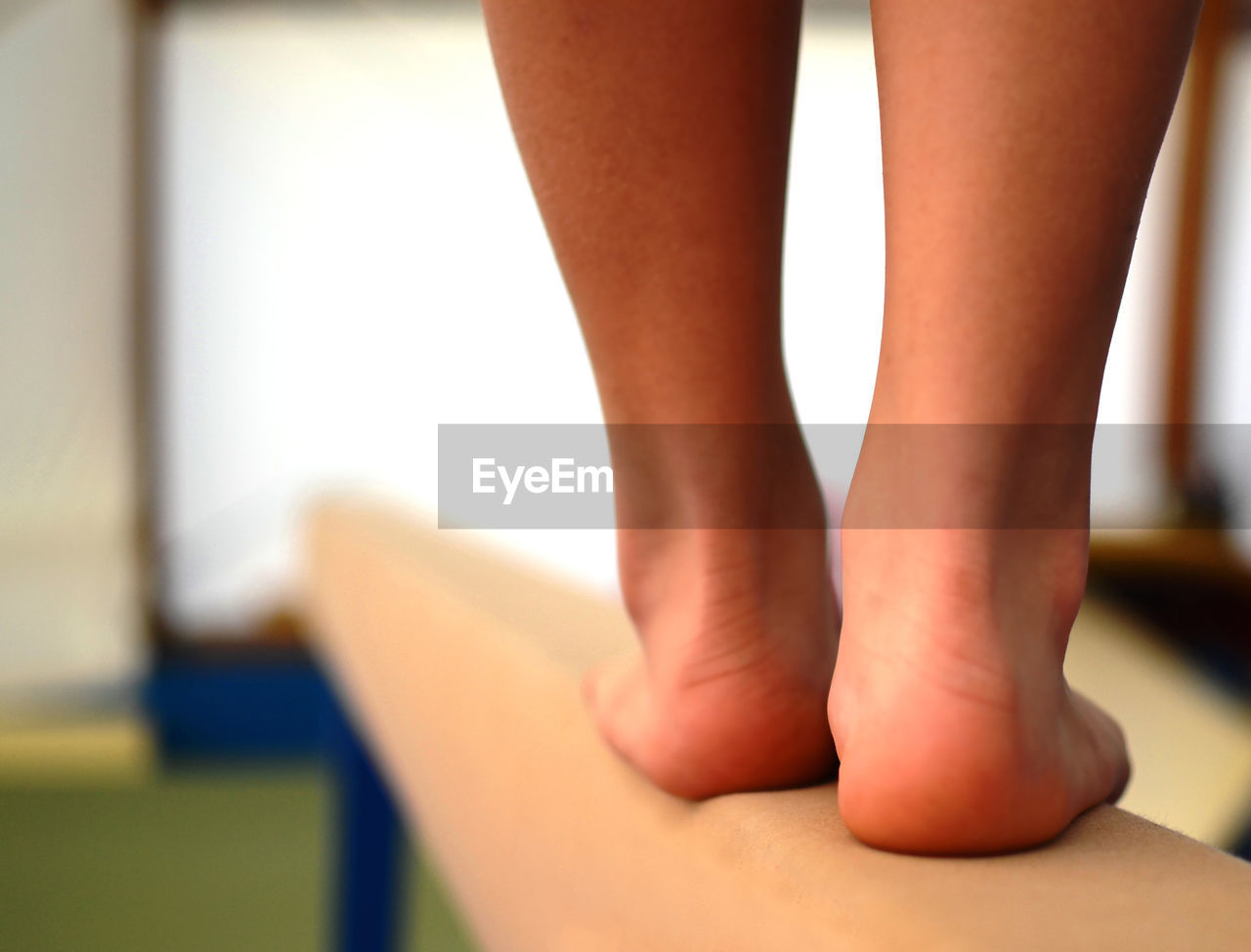 Low section of female gymnast standing on balance beam