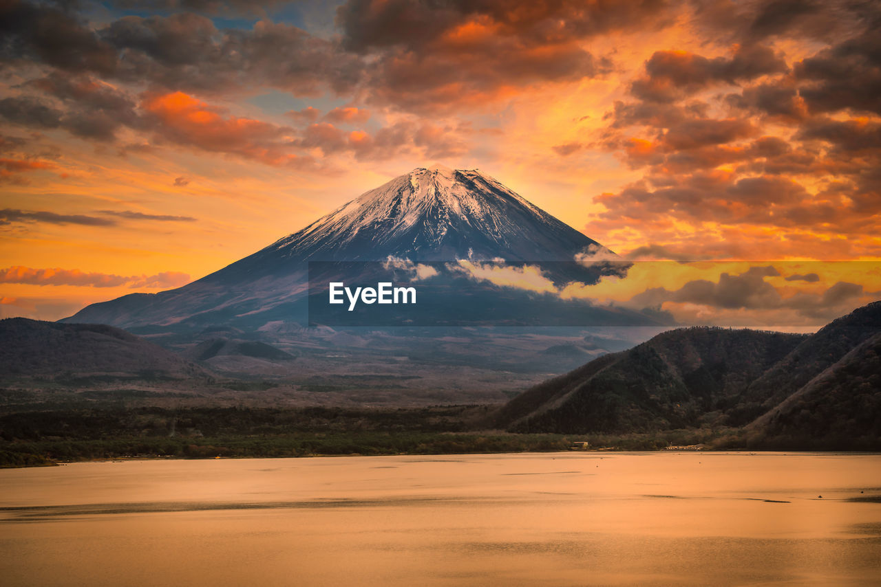 Scenic view of mount fuji mountain against cloudy sky during sunset
