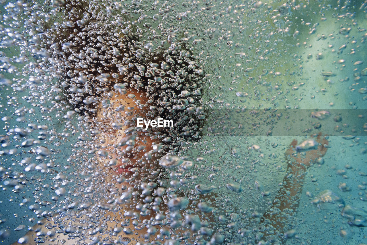 Portrait of a girl underwater in a pool with bubbles.