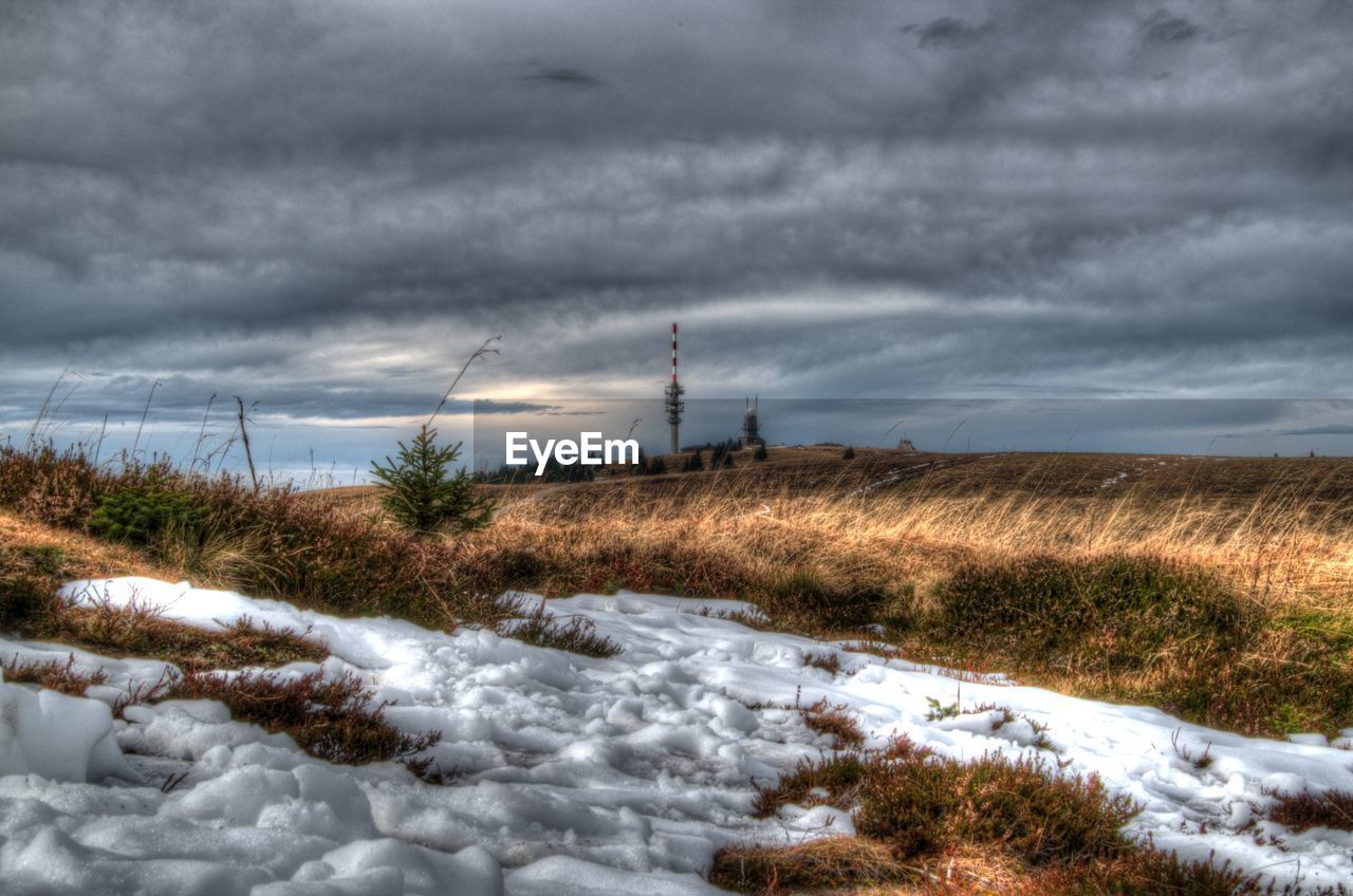 Snow on field against cloudy sky