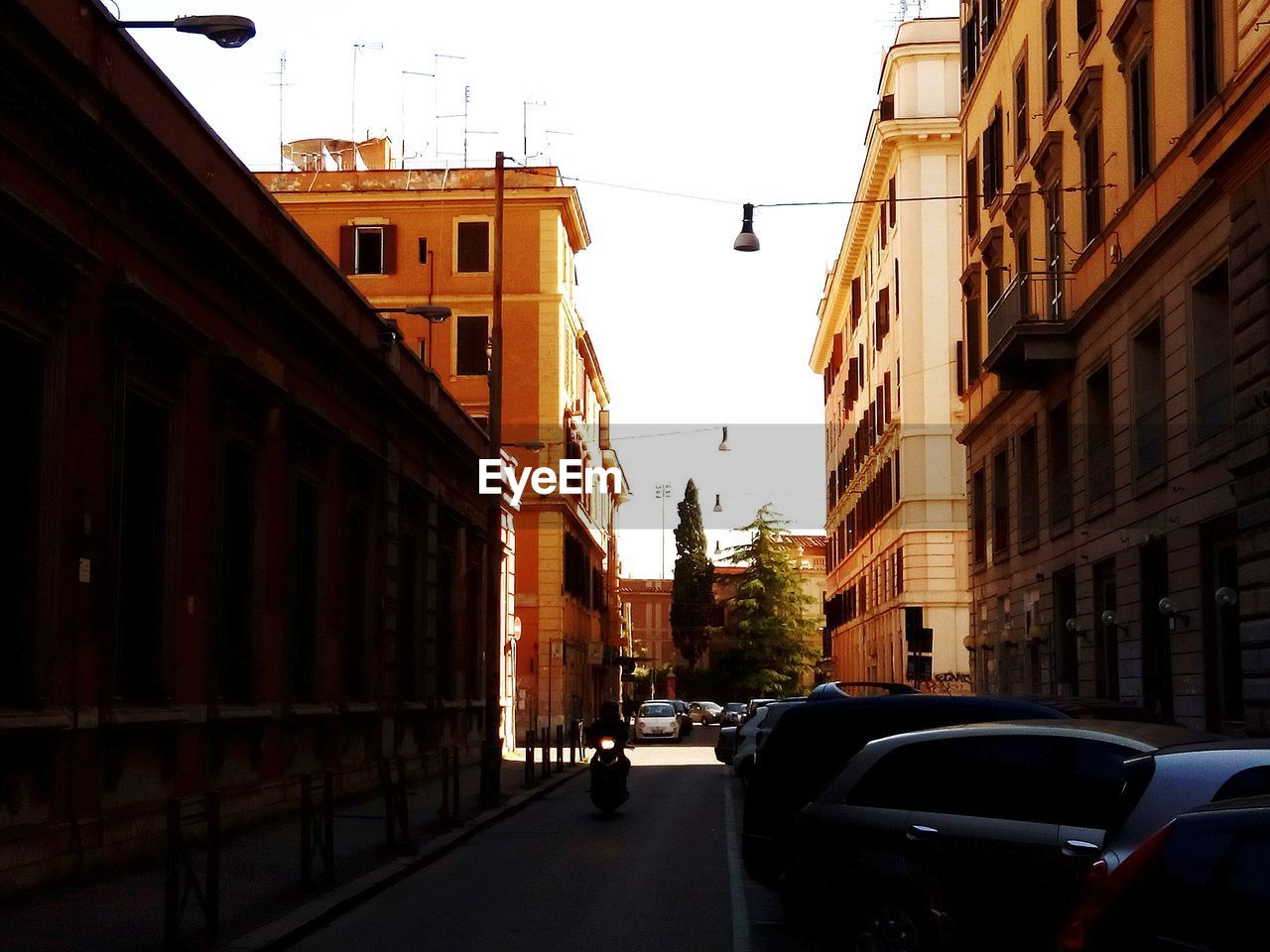 CARS ON ROAD AMIDST BUILDINGS AGAINST CLEAR SKY