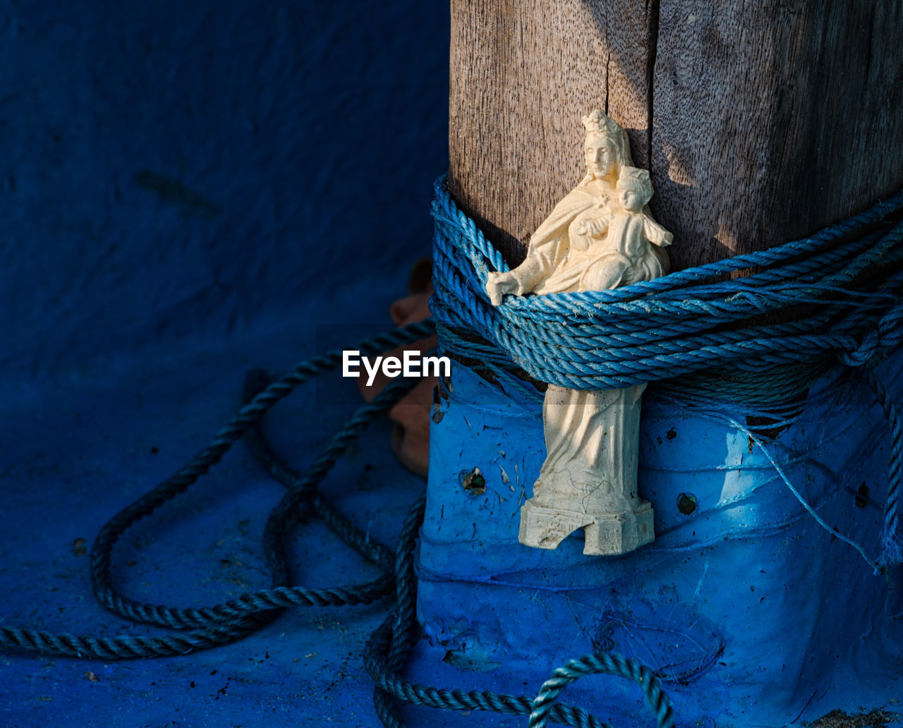 Close-up of virgin mary tied on wooden post in boat