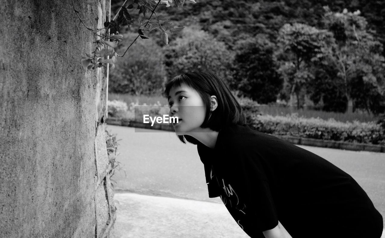 PORTRAIT OF BEAUTIFUL YOUNG WOMAN STANDING AGAINST TREES