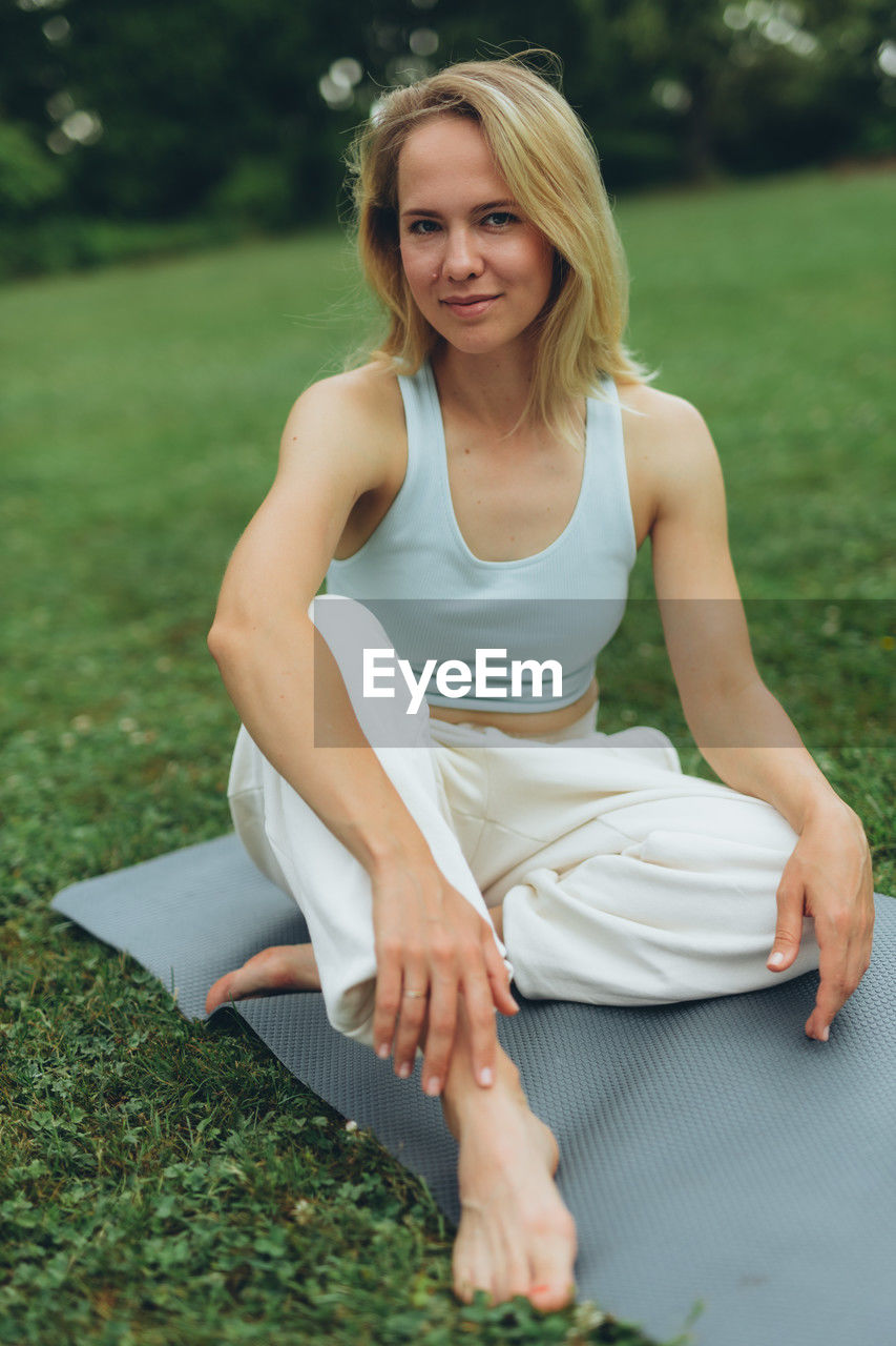 portrait of young woman sitting on grassy field