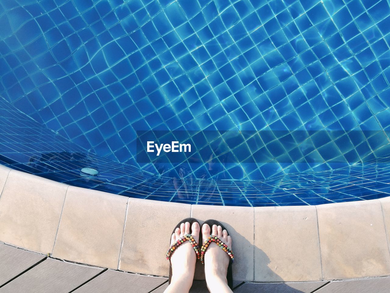 Low section of woman standing by swimming pool