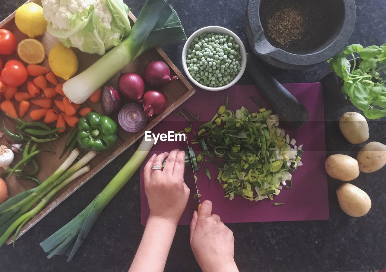 Cropped hand cutting vegetables at home