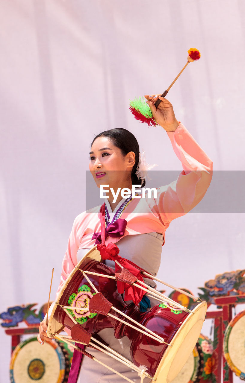 FULL LENGTH OF YOUNG WOMAN HOLDING TRADITIONAL CLOTHING