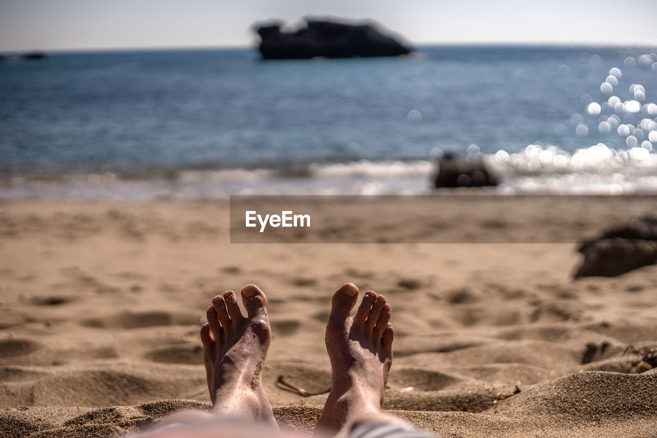 Low section of man relaxing on beach