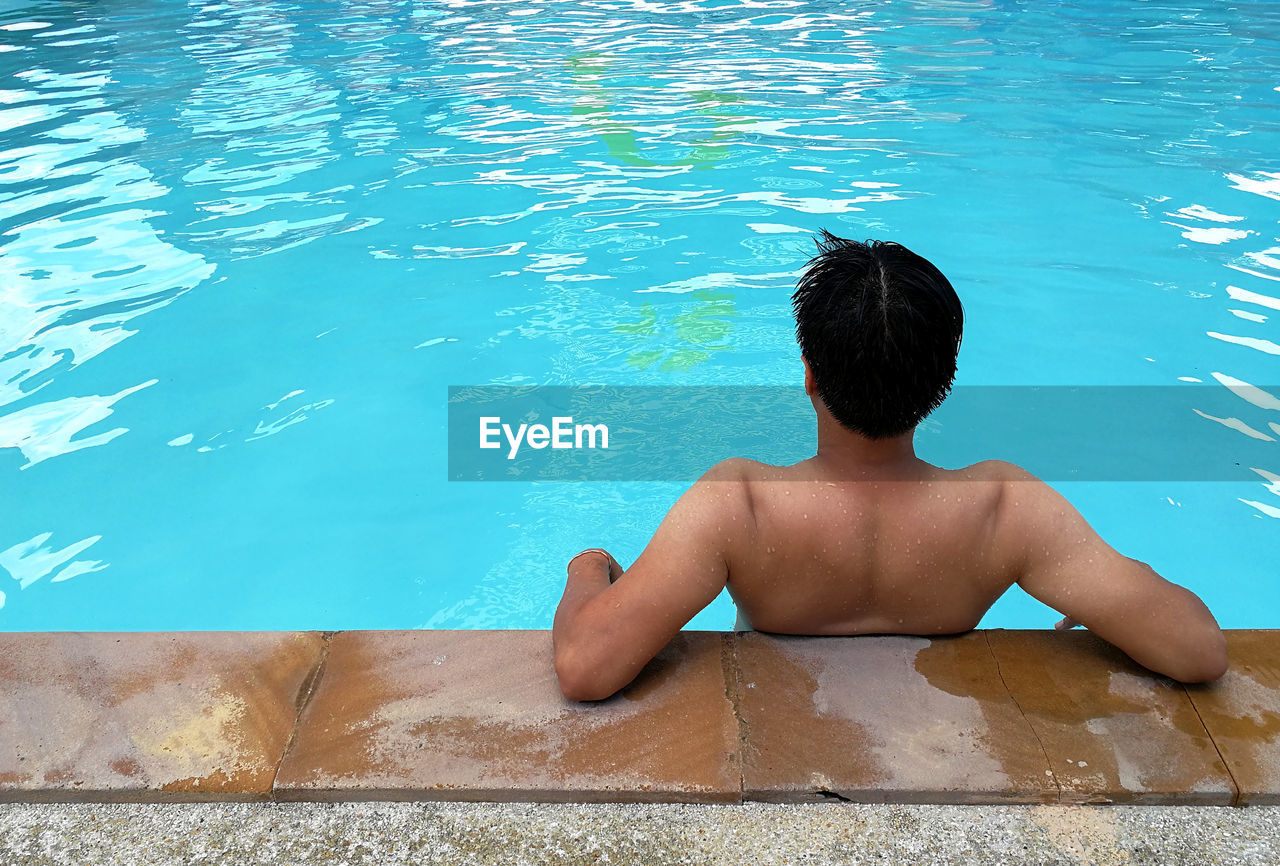 REAR VIEW OF SHIRTLESS BOY AT SWIMMING POOL