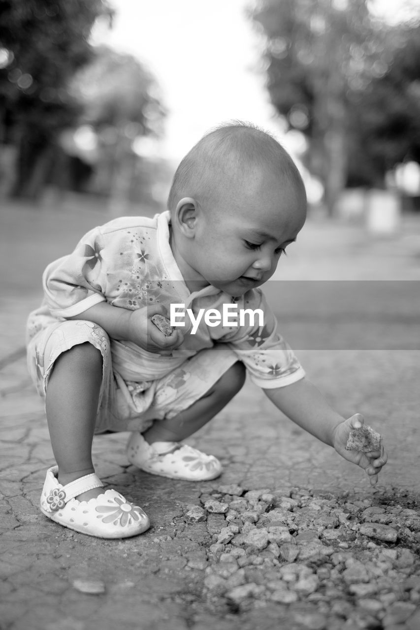 Cute baby girls playing rocks in outdoors