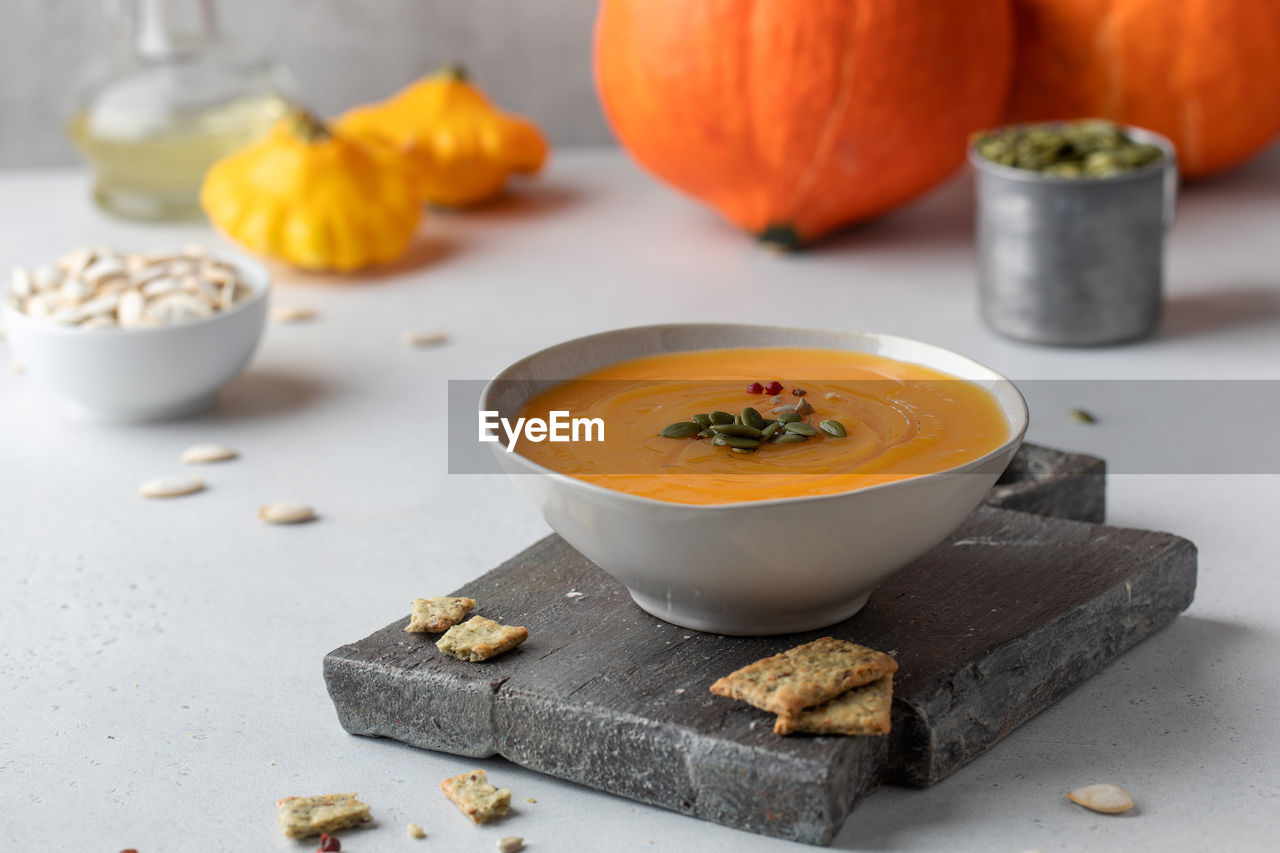Pumpkin cream soup with seeds on a wooden board. autumn dish.