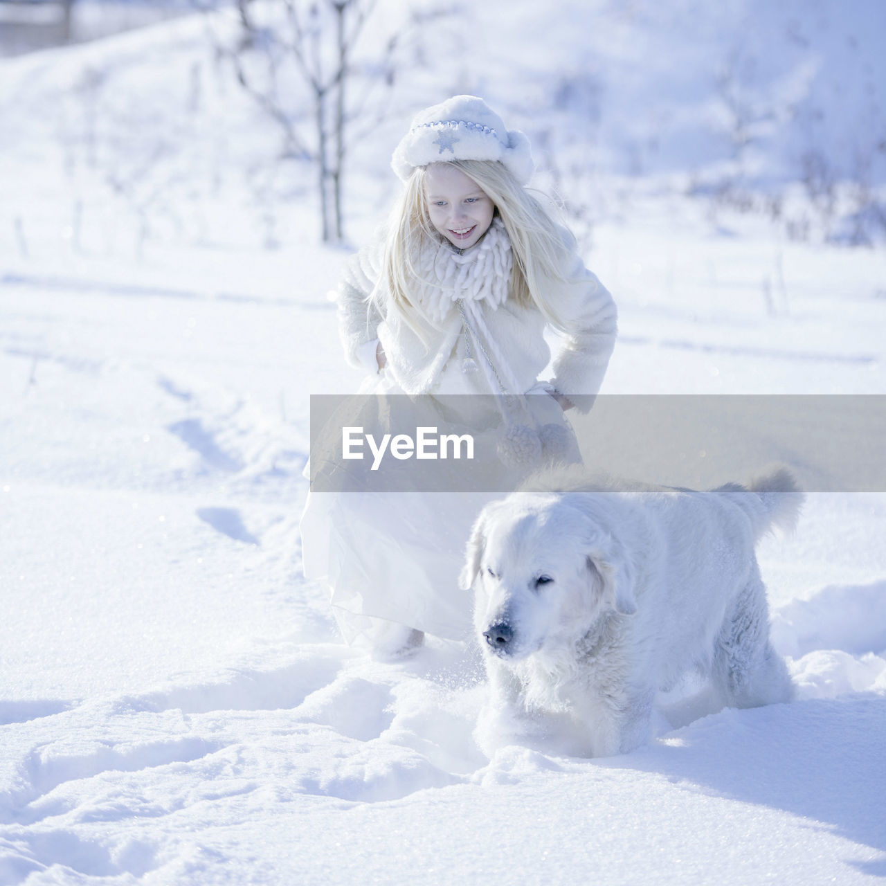 Happy girl with golden retriever on snow covered field