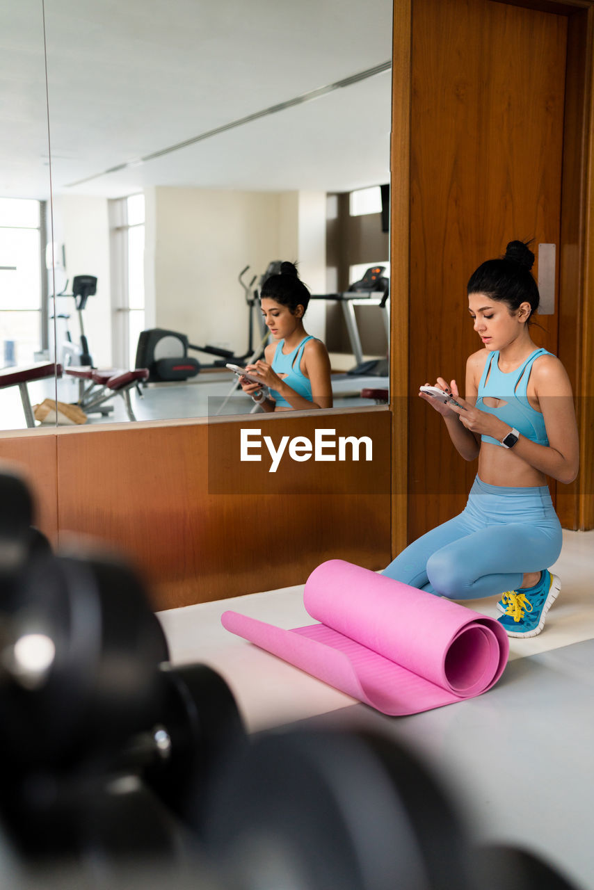 Young woman training at the gym using her phone