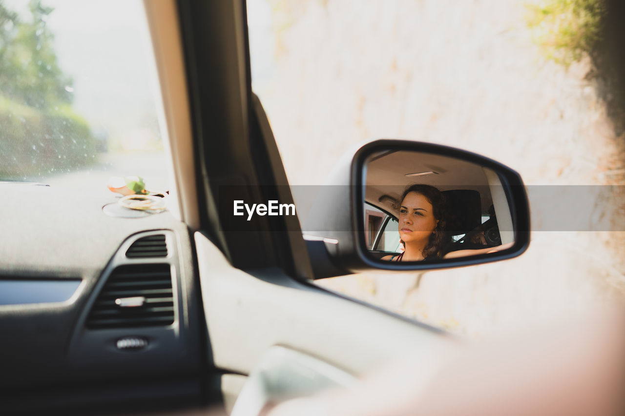 Close-up of woman reflection in side-view mirror