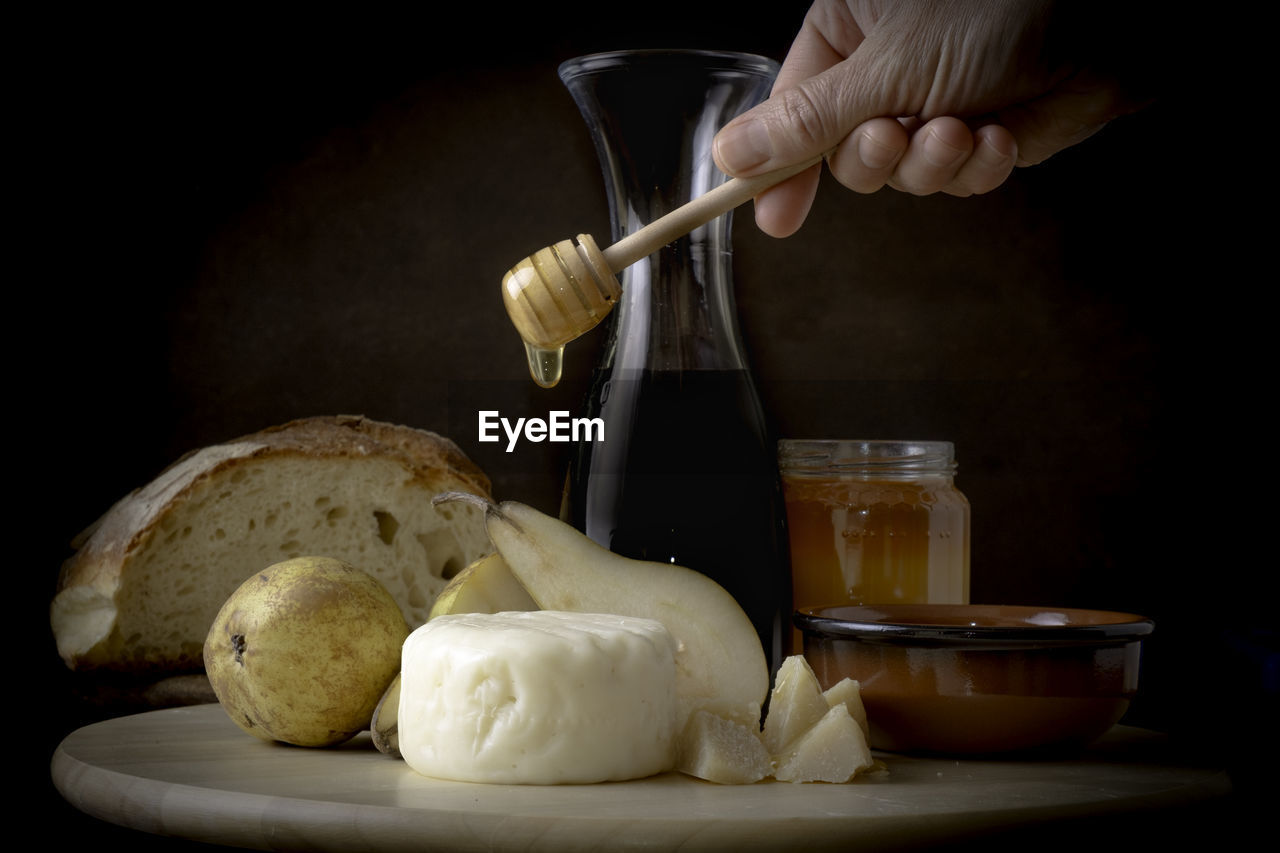 Cropped hand of man preparing food on cutting board against black background