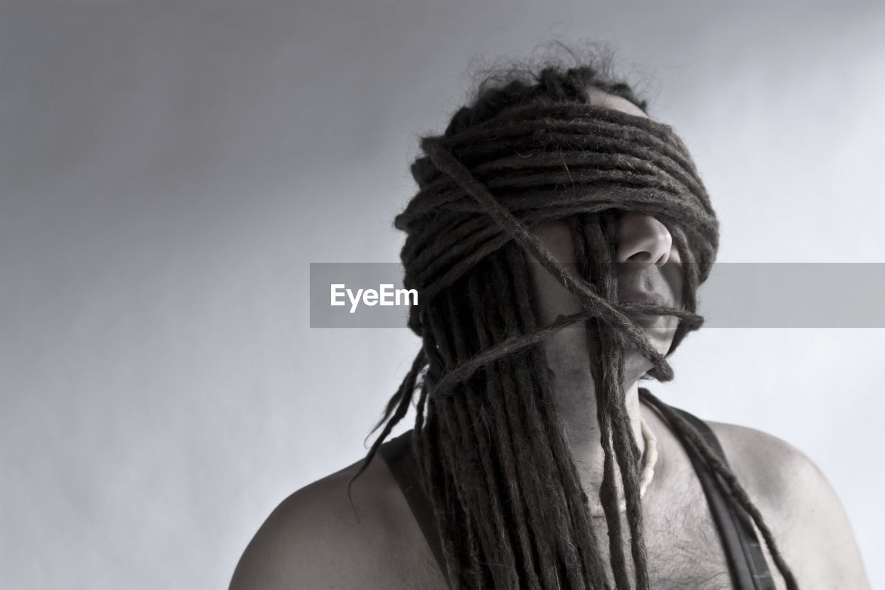 Man with face covered by dreadlocks against white background