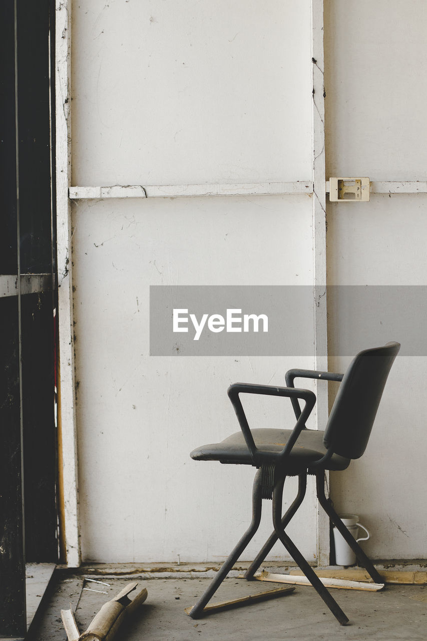 Empty chair on table against wall in old building