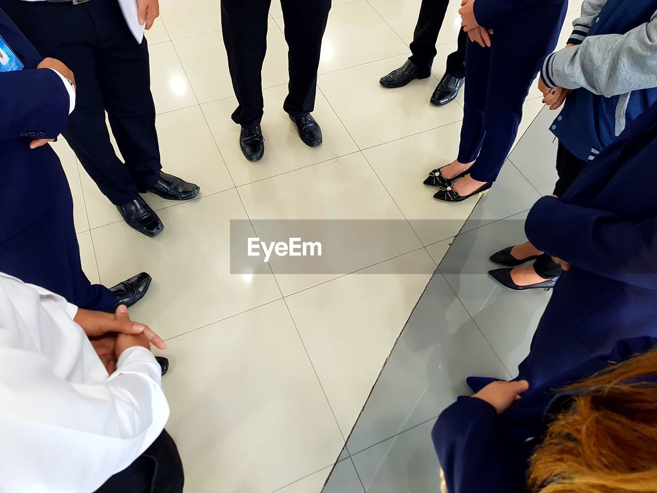 Low section of colleagues standing on tiled floor