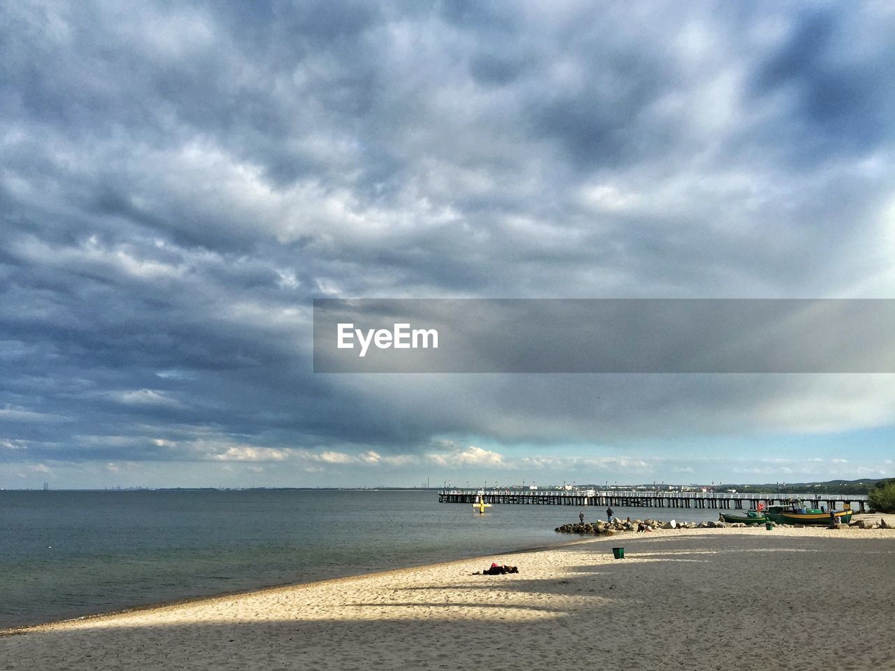 View of calm beach against cloudy sky