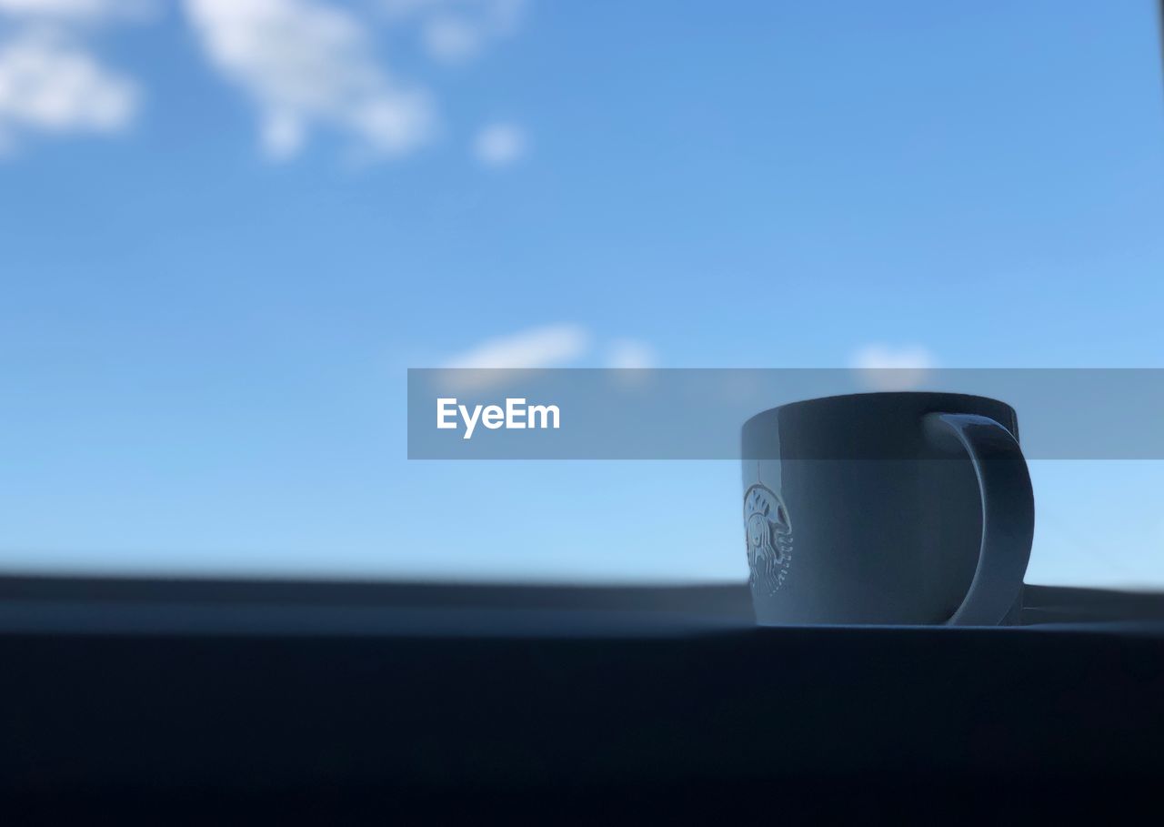 CLOSE-UP OF COFFEE CUP AGAINST BLUE SKY