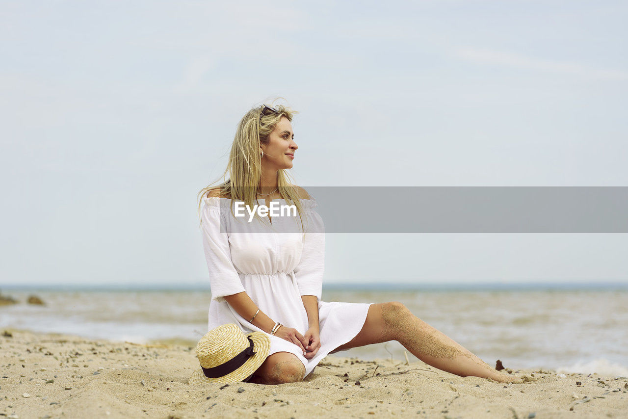 beach, land, one person, blond hair, sea, water, adult, women, sand, nature, sky, relaxation, leisure activity, holiday, trip, vacation, sitting, hairstyle, photo shoot, long hair, clothing, young adult, full length, lifestyles, summer, horizon over water, day, female, copy space, tranquility, horizon, casual clothing, person, wellbeing, beauty in nature, outdoors, contemplation, barefoot, sunlight, human leg, yoga, smiling, looking, exercising, carefree, travel, happiness, portrait photography, emotion, meditating, spring, sunny, tranquil scene, fashion, water's edge, solitude, sports, environment, zen-like, portrait, shore, looking away