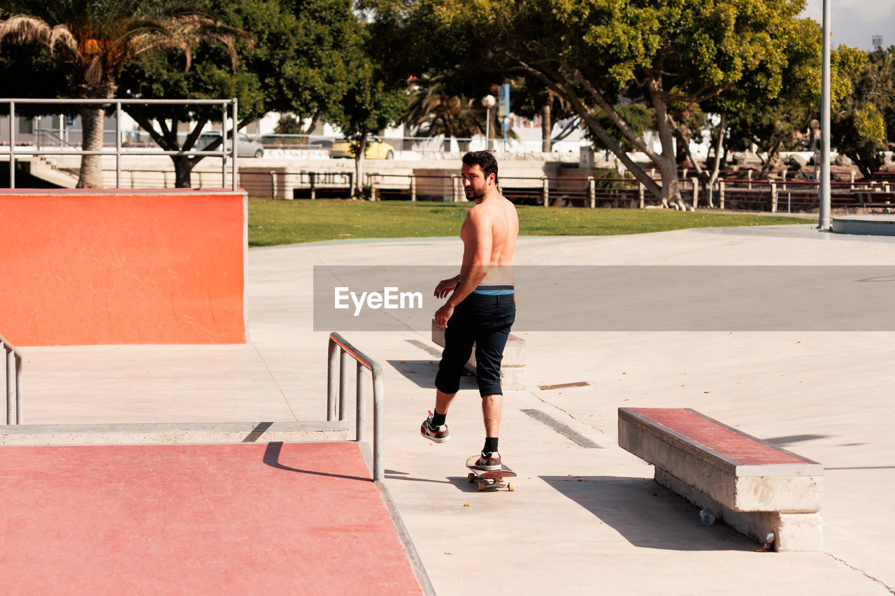 Man riding skateboard in urban street skatepark. casual guy wearing shorts and t-shirt.