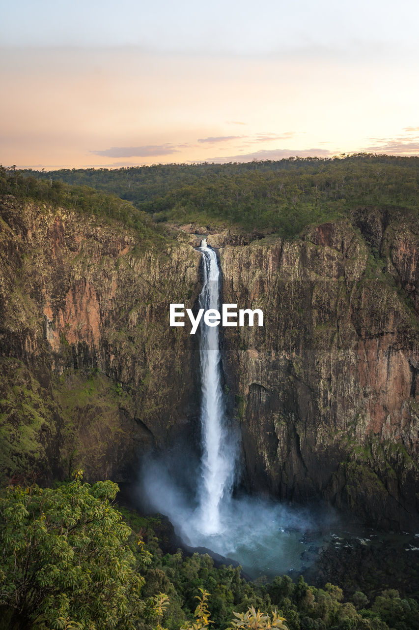 Spectacular aerial view of powerful wallaman falls flowing through rocky cliff in girringun national park covered with lush tropical vegetation in queensland