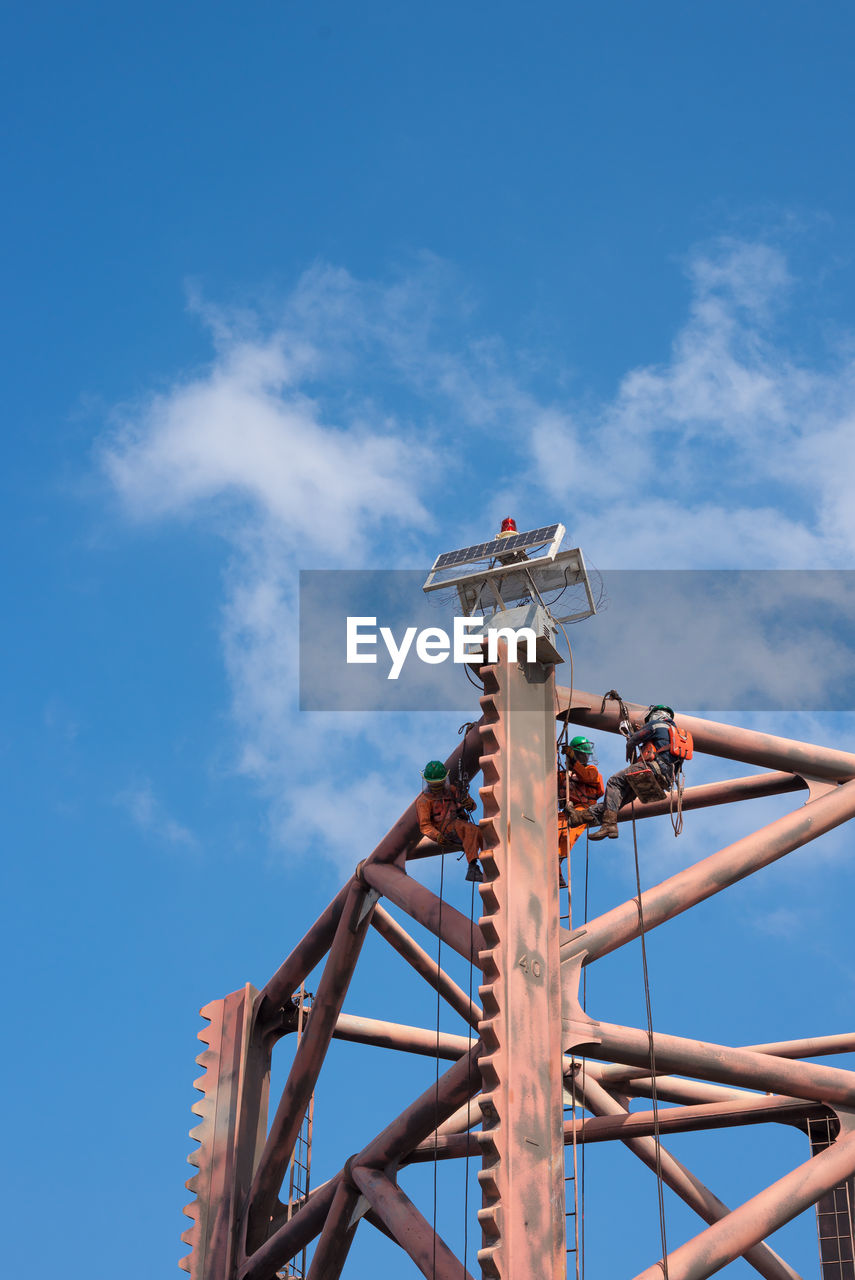 LOW ANGLE VIEW OF CRANE AGAINST BLUE SKY