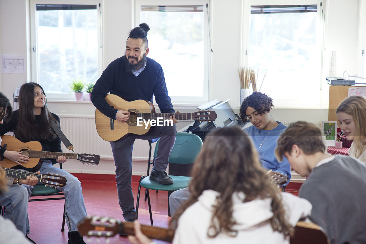 Teenagers attending guitar lesson