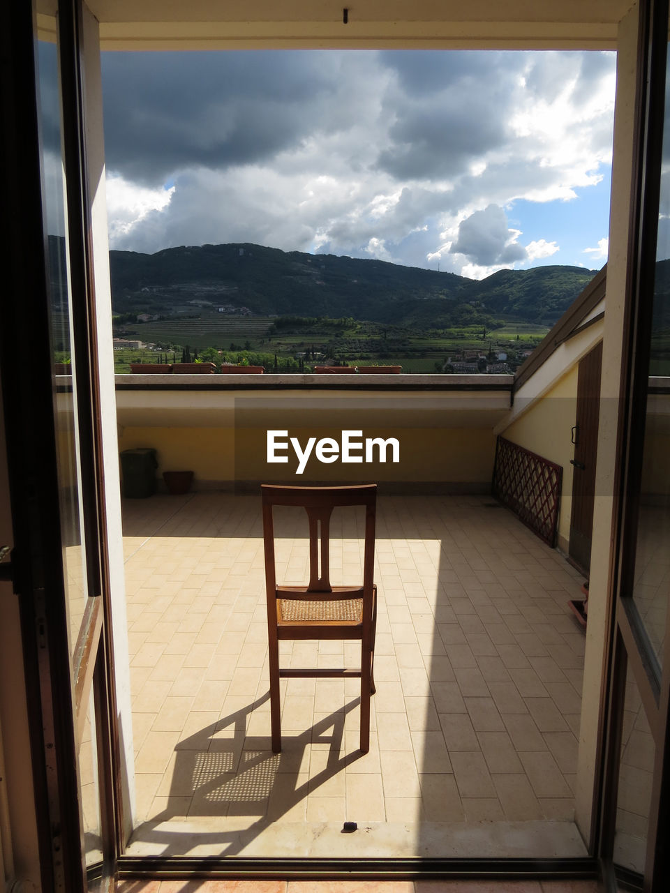 CHAIRS AND TABLE ON BALCONY AGAINST MOUNTAINS