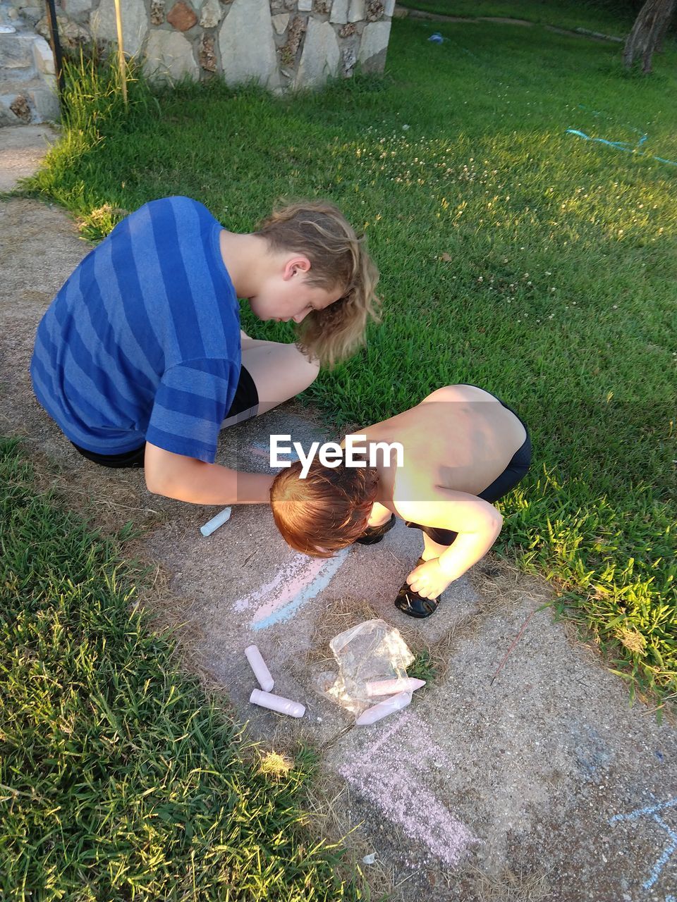 High angle view of brothers chalk drawing on footpath in yard