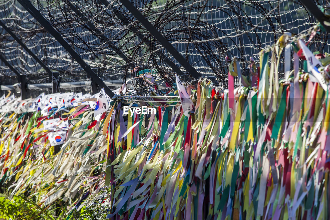Colorful ribbons hanging to barbed wire fence