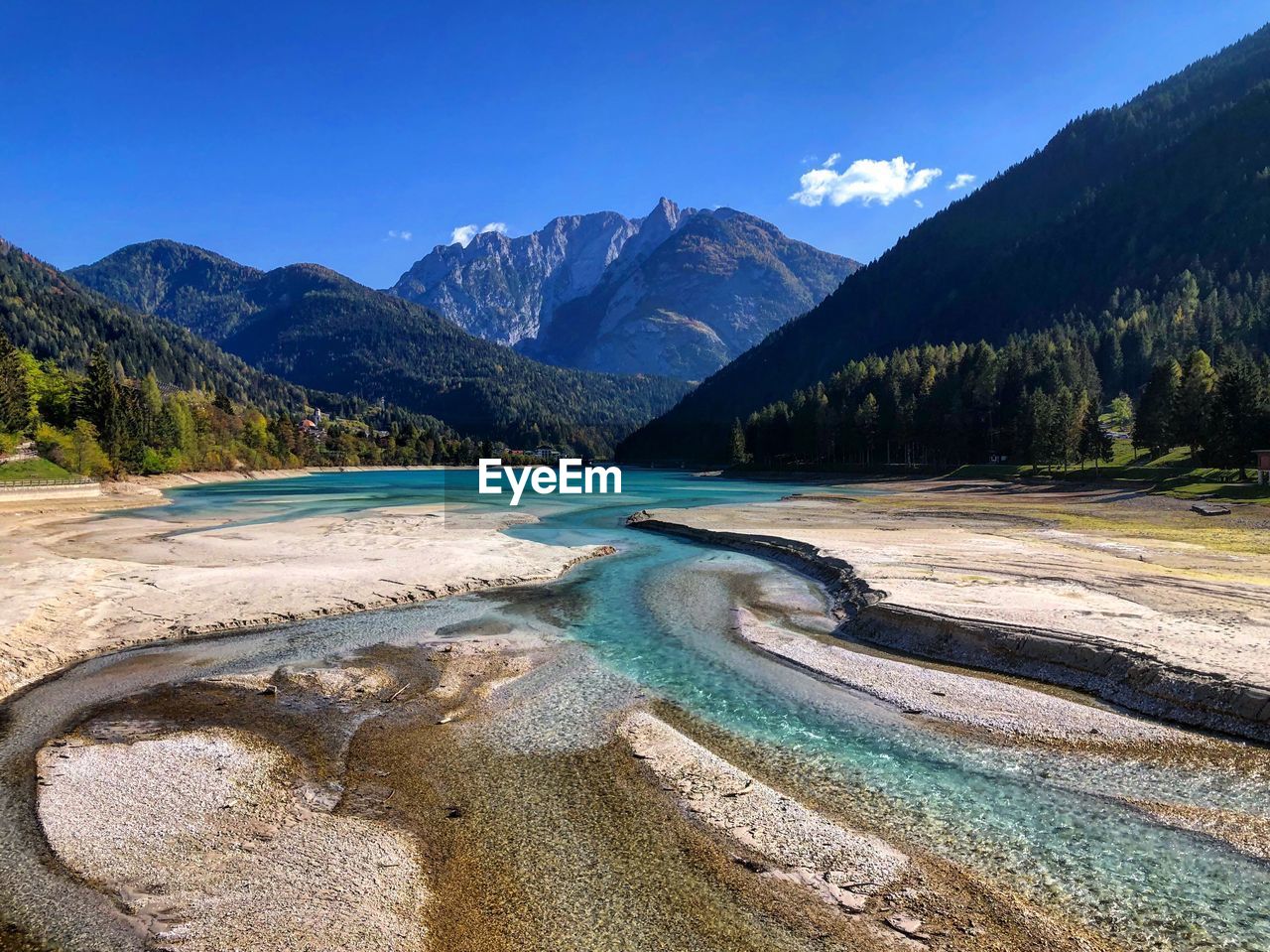 Scenic view of lake by mountains against blue sky