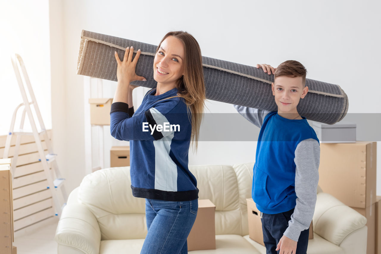 Portrait of mother and son carrying carpet