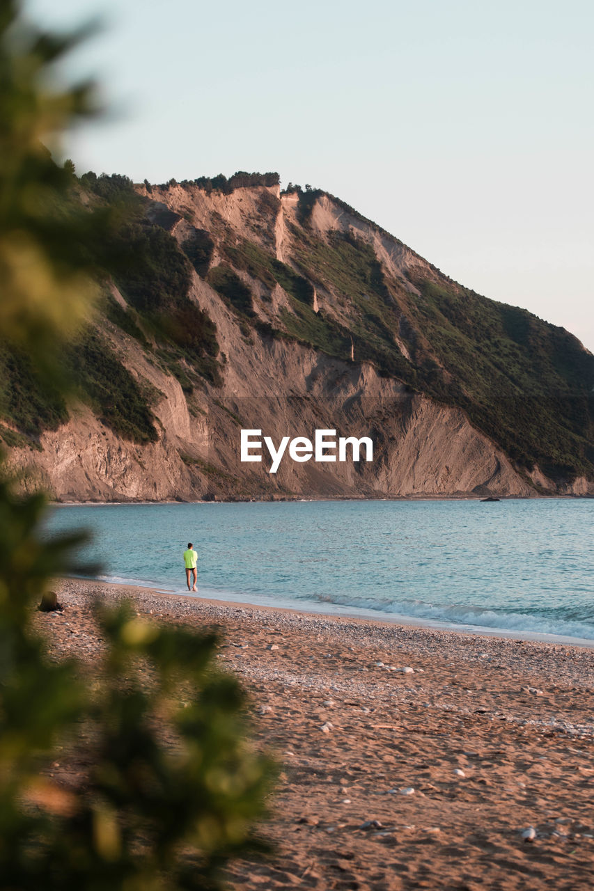 Distant view of man at beach against mountain