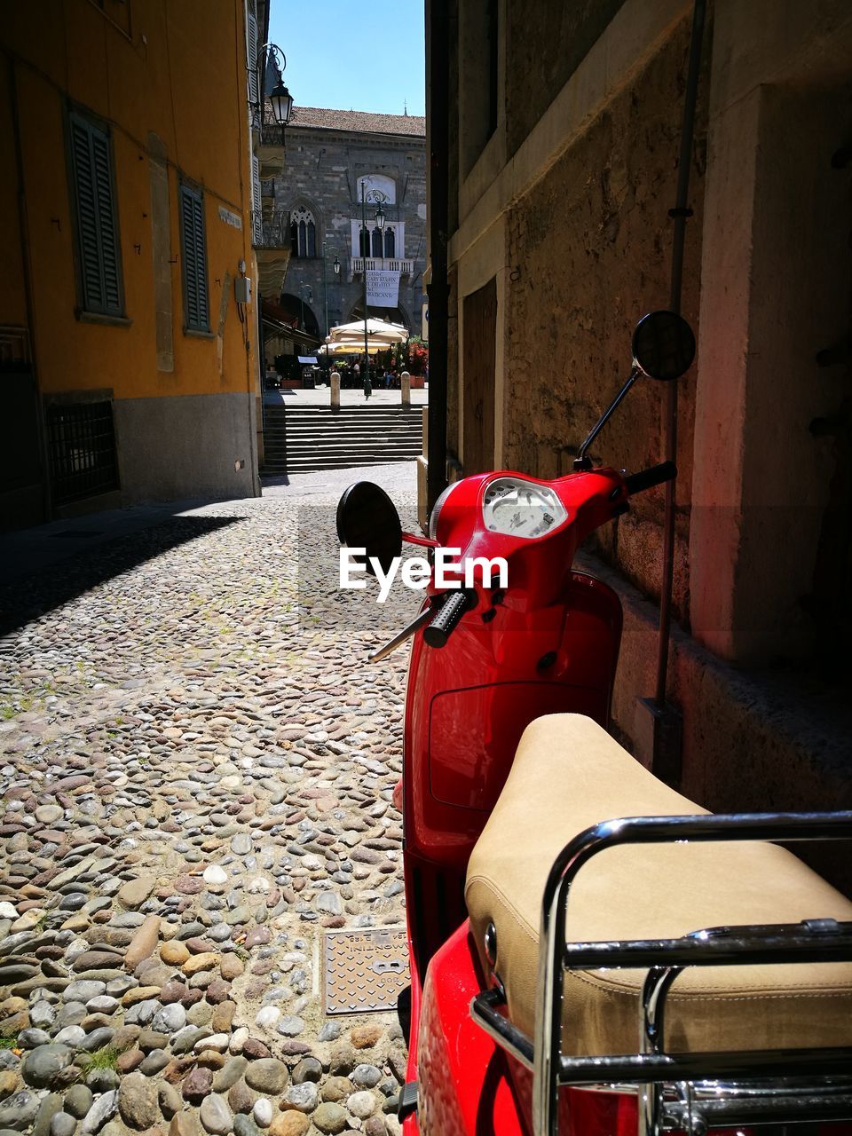 RED MOTOR SCOOTER ON STREET AGAINST BUILDING