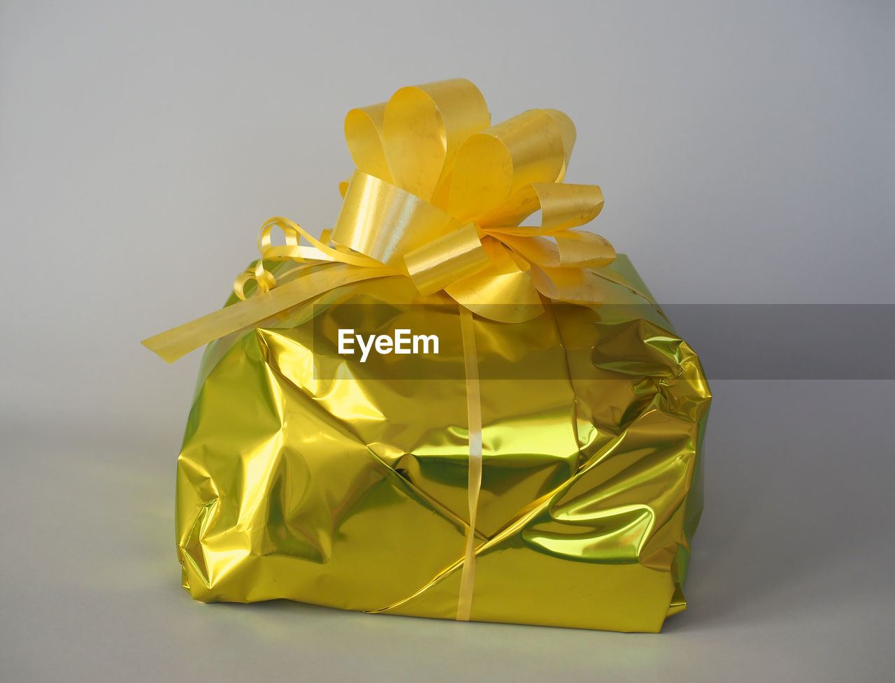 yellow, studio shot, gift, paper, gray background, petal, gold, indoors, origami, no people, gray, origami paper, art, wrapping paper, ribbon, wrapped, celebration, surprise, flower, single object, box, bow, shiny, cut out, still life, tied bow, art paper, wealth, holiday, container, gift box, copy space, emotion