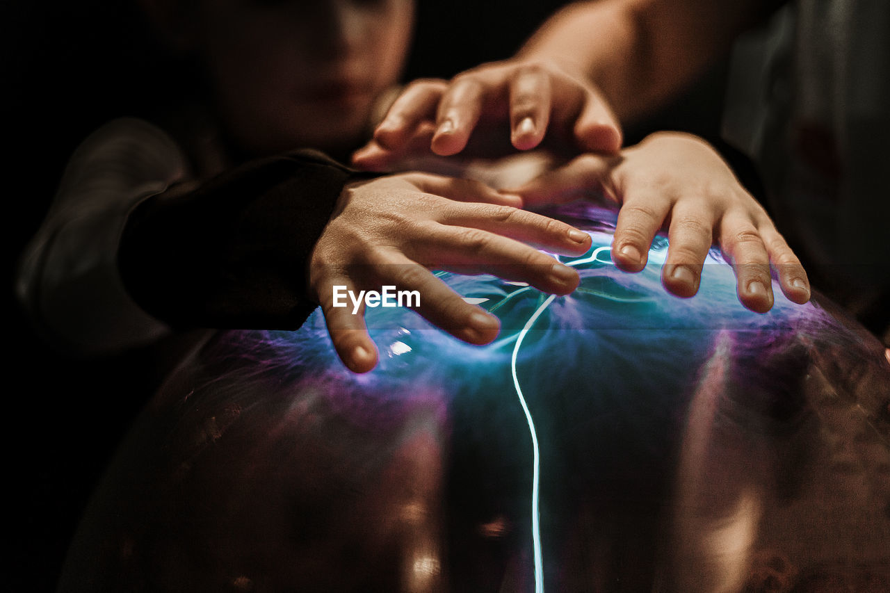 Close-up of people touching illuminated equipment