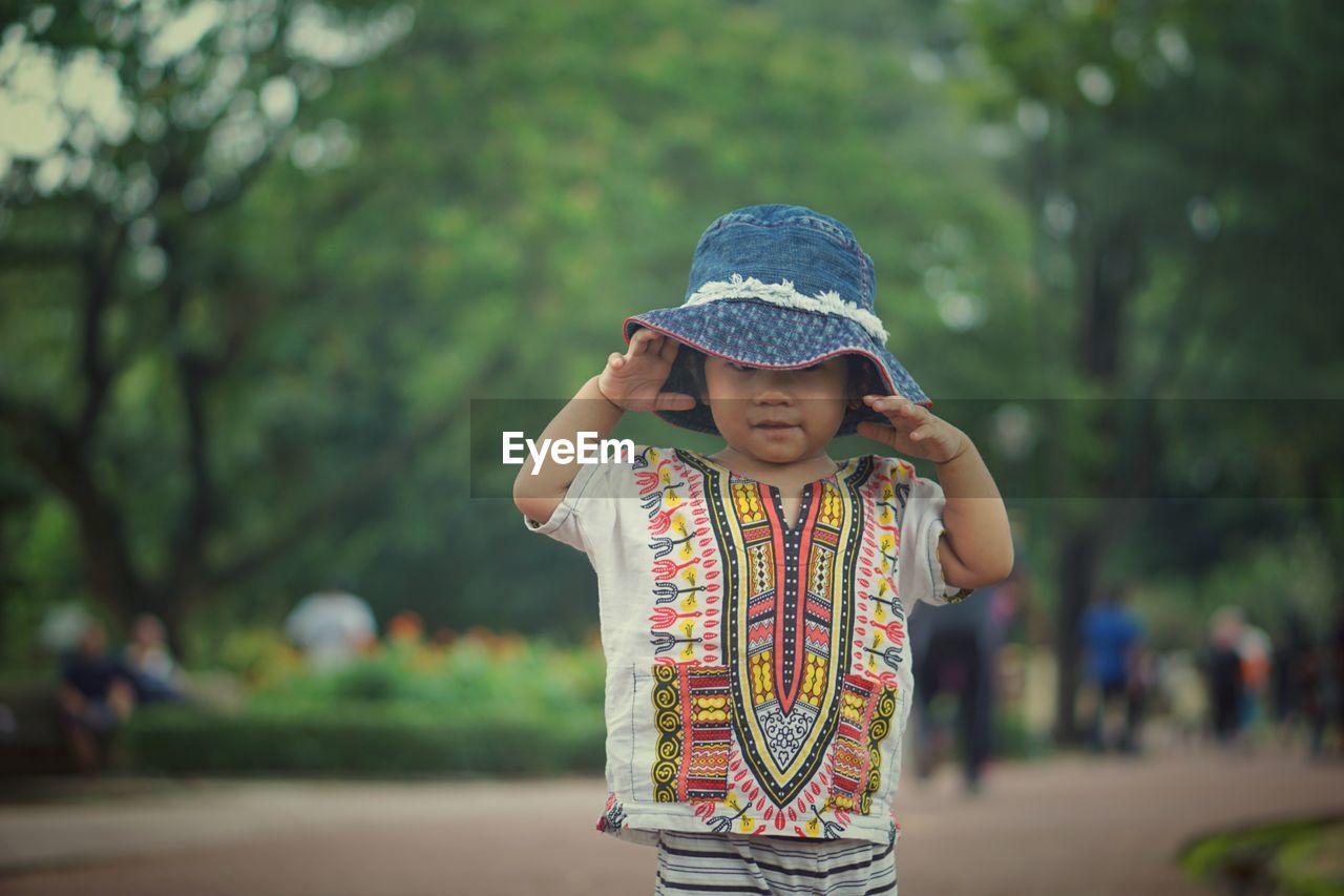 Portrait of cute girl wearing hat while standing on road 