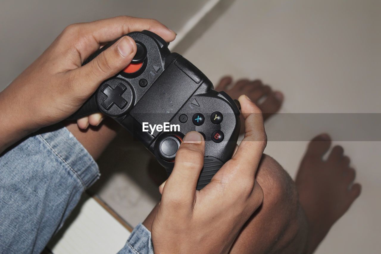 Low section of boy playing video game at home