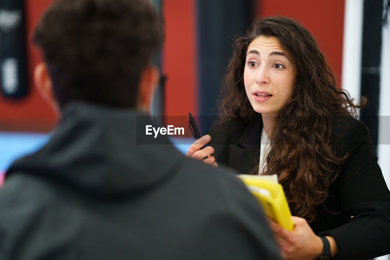 portrait of young woman looking away while standing in office