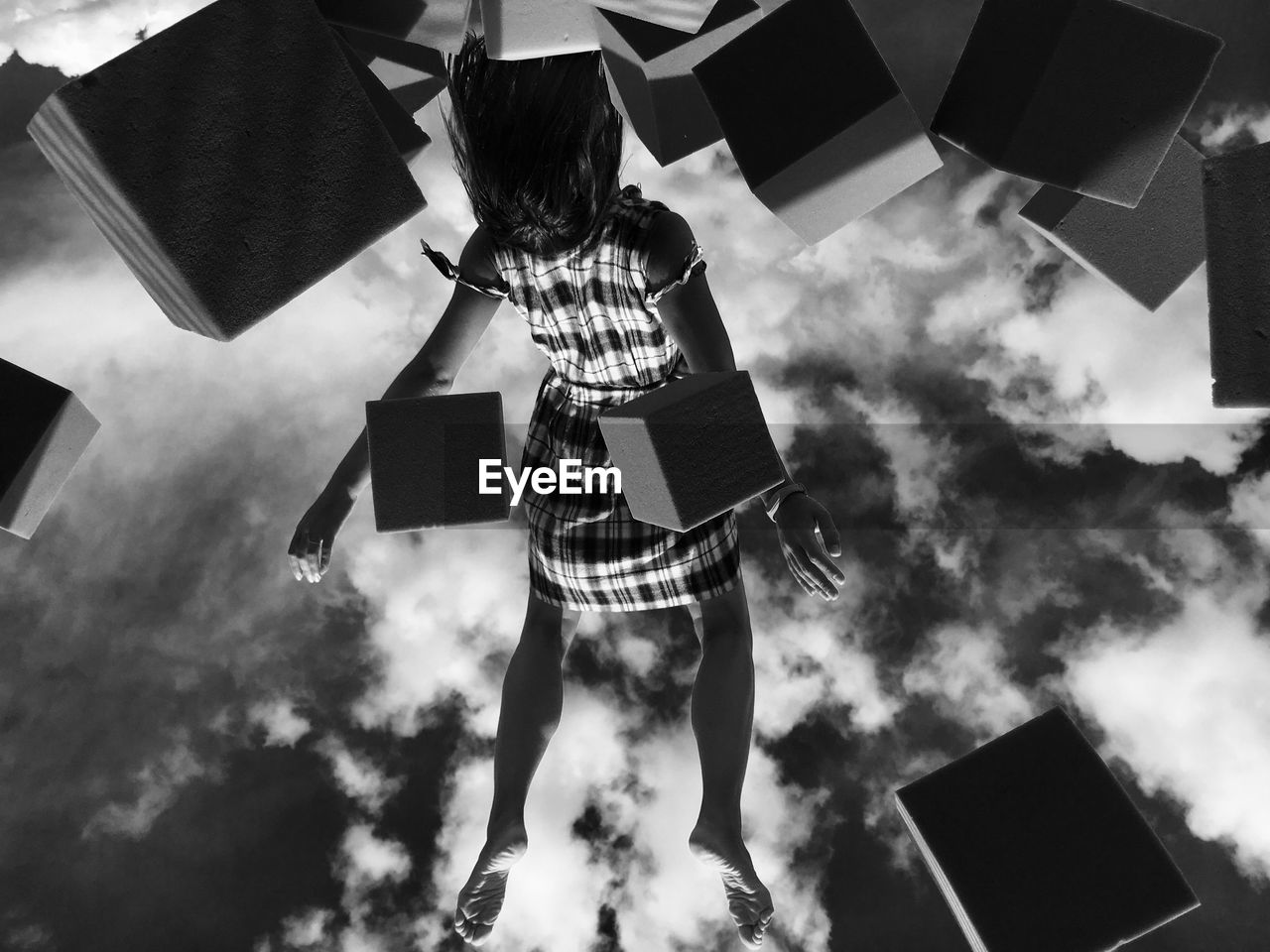 Low angle view of woman levitating amidst blocks against sky