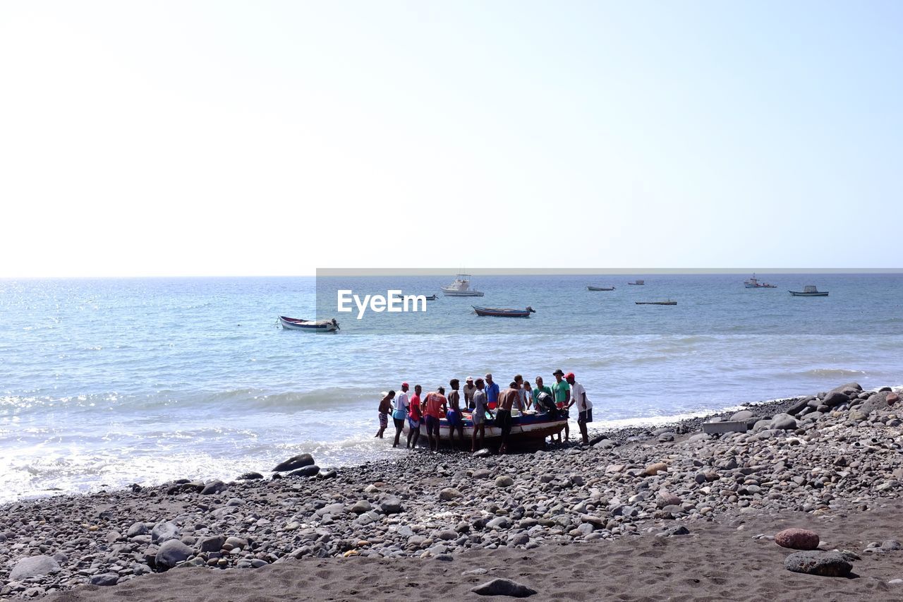 PEOPLE IN SEA AGAINST CLEAR SKY