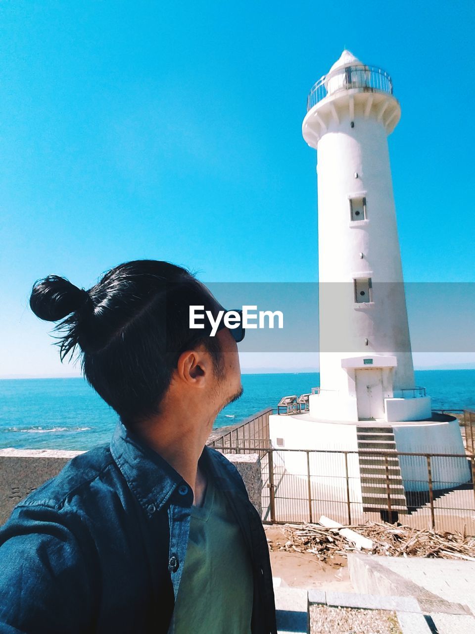 Man looking at lighthouse against sky