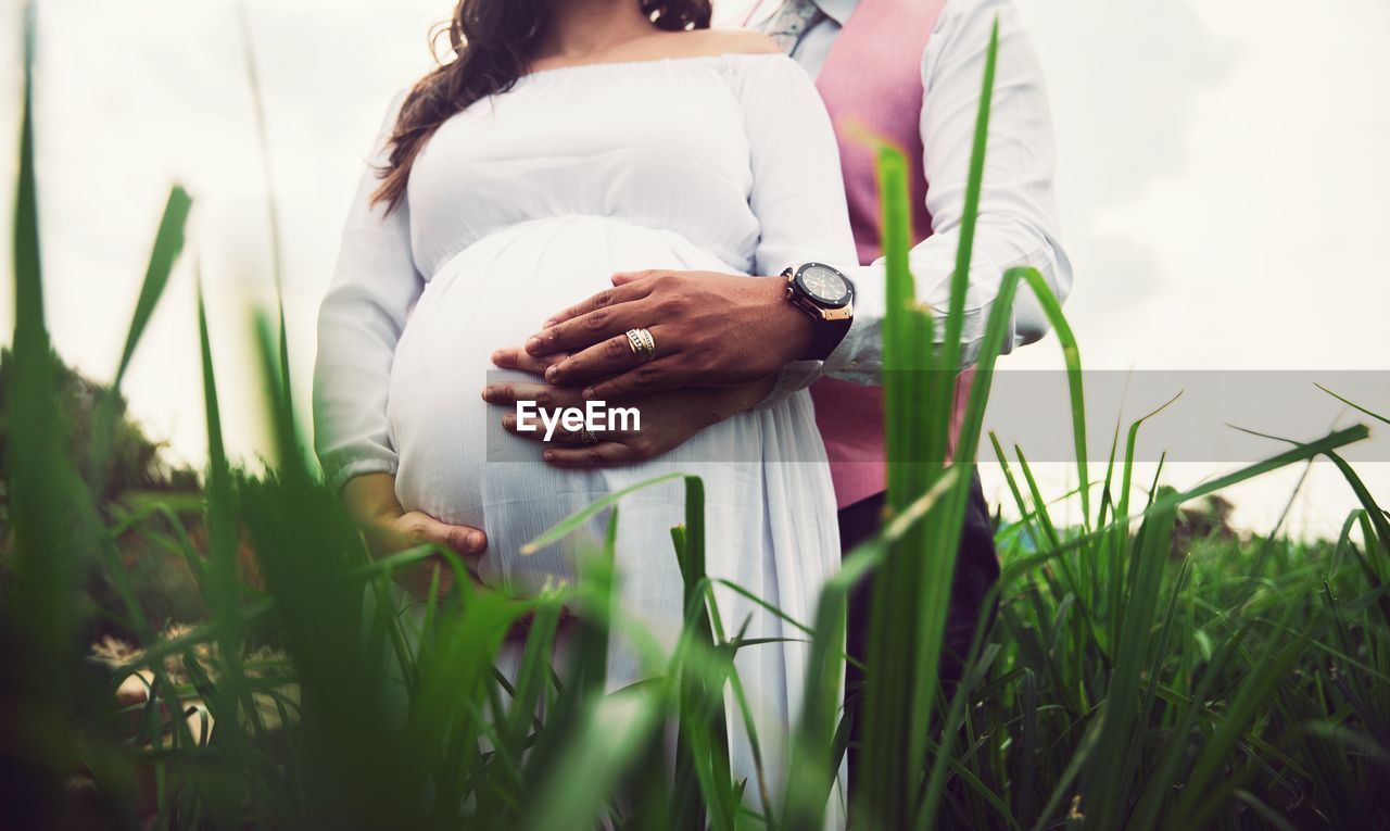 MIDSECTION OF WOMAN STANDING ON GRASS