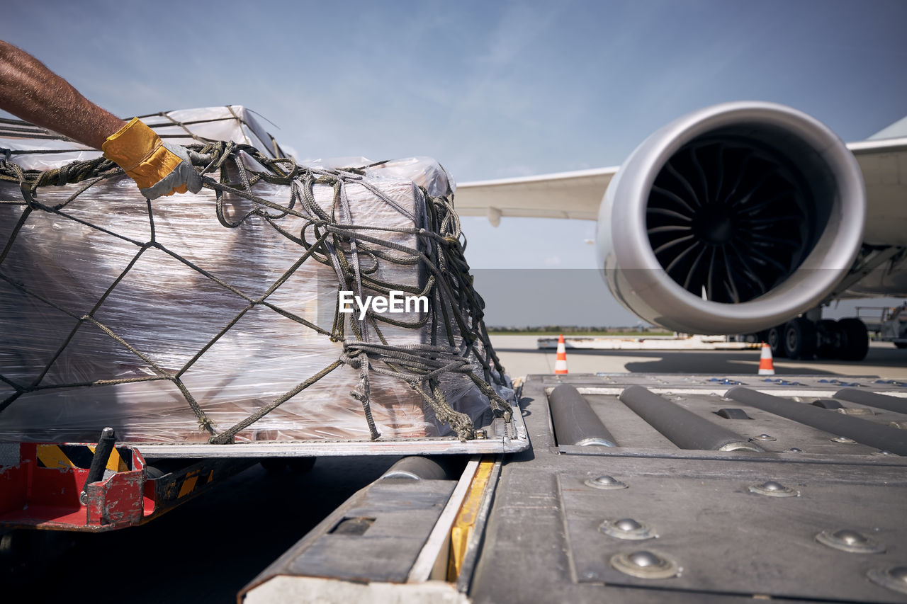 Hand of ground crew during unloading freight airplane. cargo containers against jet engine of plane.