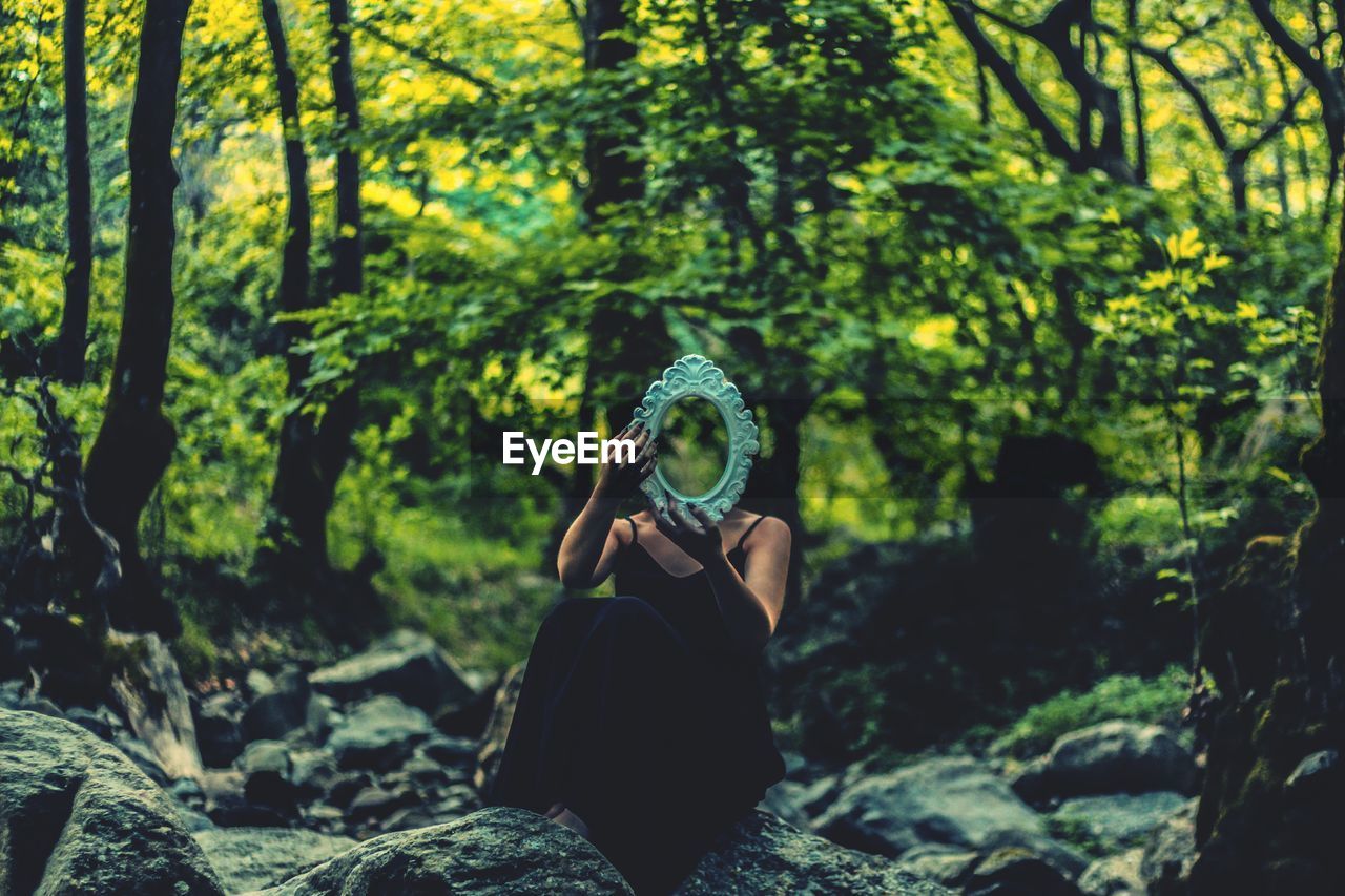 Young woman with mirror in forest